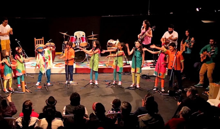 Niños y jovenes en el escenario con instrumentos musicales