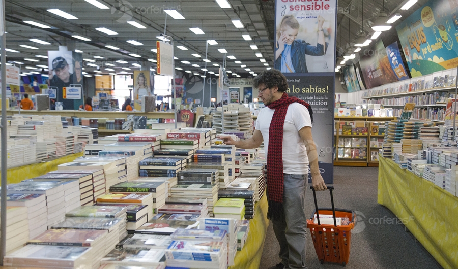 Hombre viendo libro en estand de la Feria del Libro