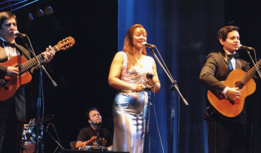 Dos hombres con guitarra y mujer cantando en el escenario