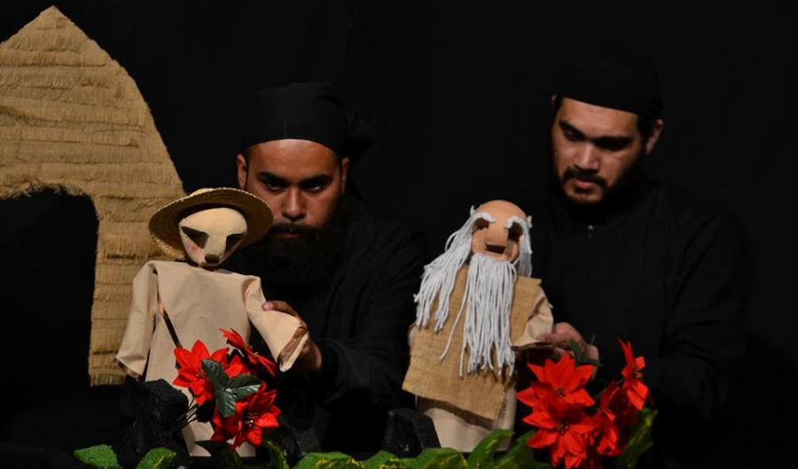 Hombres manejando los títeres en el escenario con flores