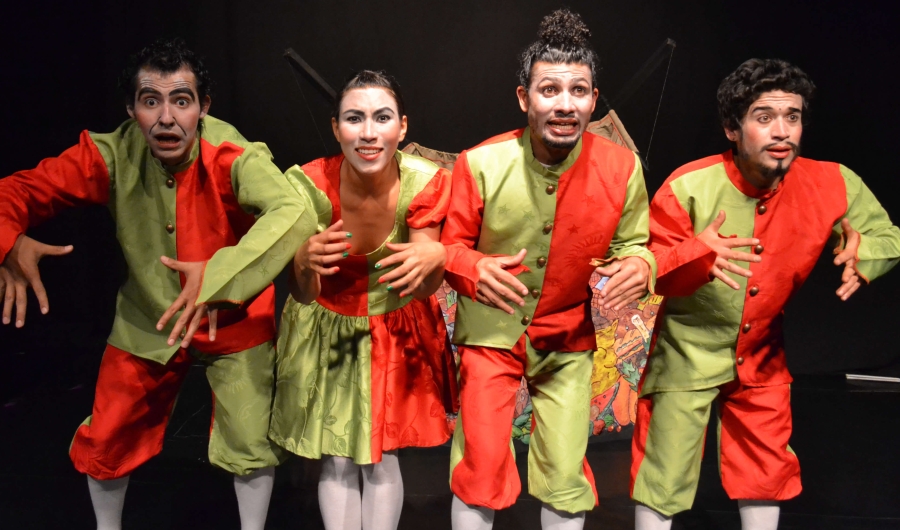 Cuatro actores posando en el escenario, vestidos de verde y naranja