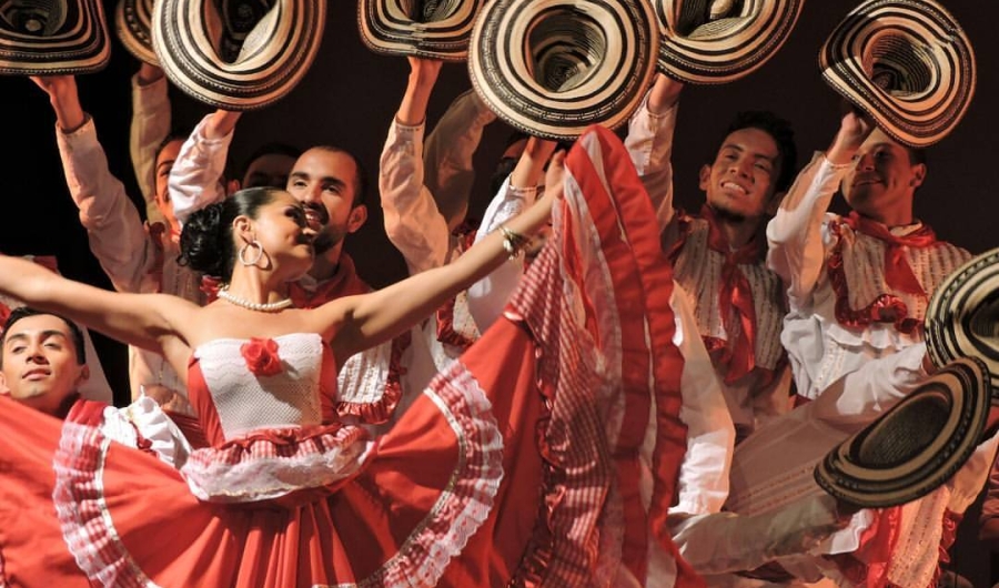 Bailarines vestidos de rojo y blanco con sombreros danzando.