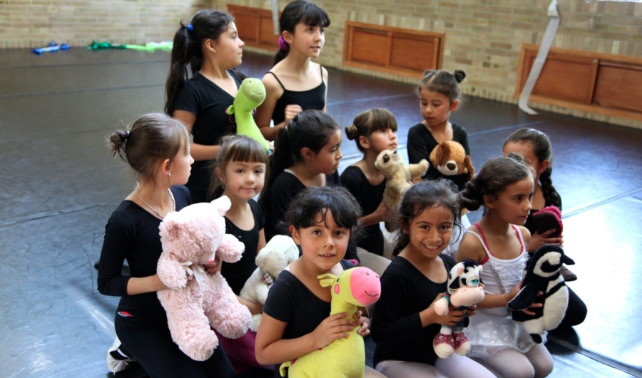 Niñas con muñecos de peluche y tela en recinto cerrado