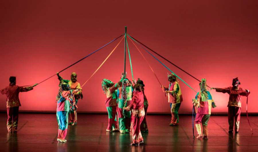 Grupo de bailarines con  lazos de colores entrelazados en el escenario