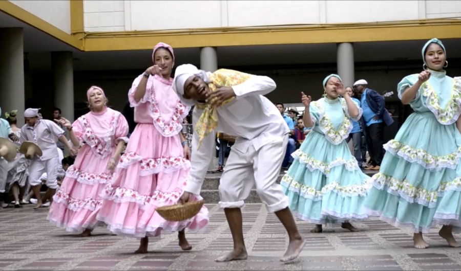 Mujeres bailando y un hombre entre ellas vestido de blanco