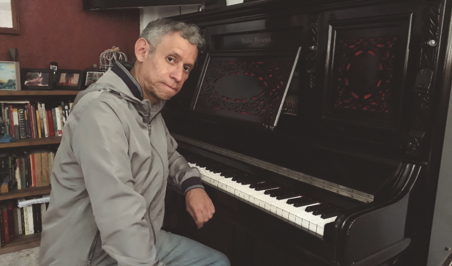 Hombre posando frente a la cámara en estudio con piano