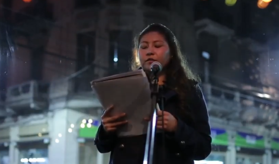 Joven mujer leyendo un texto en una calle durante la noche.