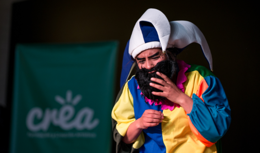 Hombre actuando vestido con traje de colores, gorro y barba negra