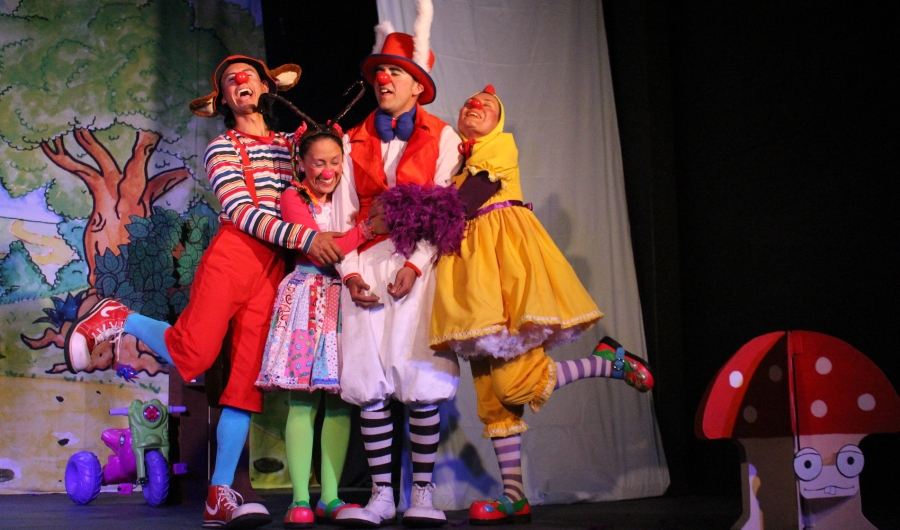 Actores adultos y niños vestidos de colores en un escenario