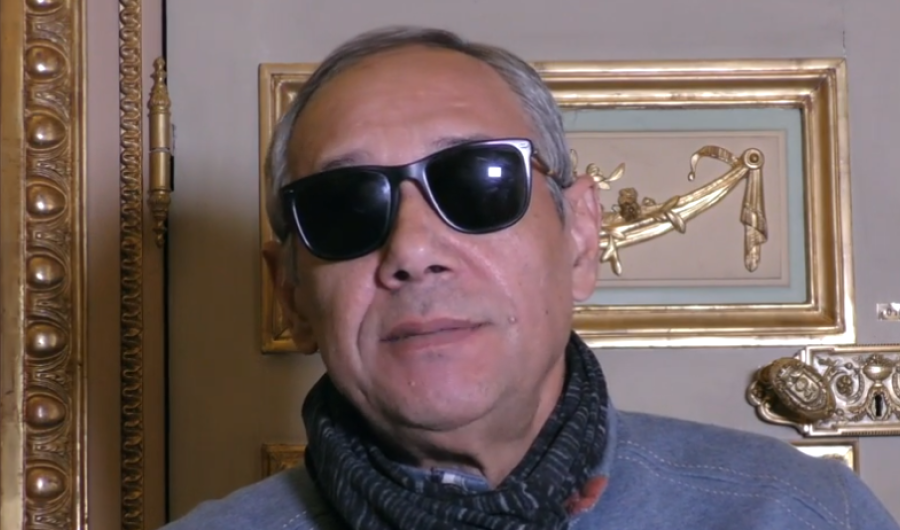 Escritor con gafas oscuras dando una entrevista - Captura de pantalla de entrevista con Casa América.