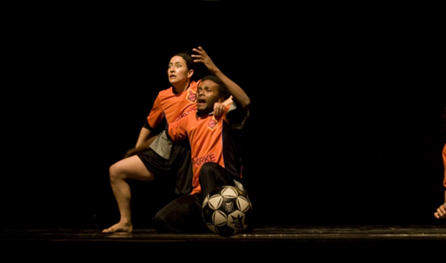 Actores en escena vestidos de jugadores con pelota de futbol