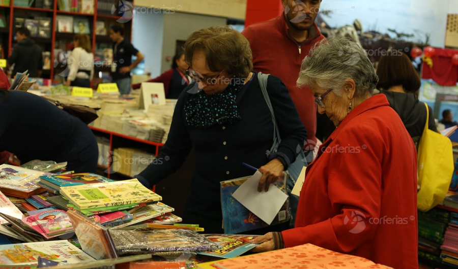 Mujeres viendo libros en estante Corferias - FILBo