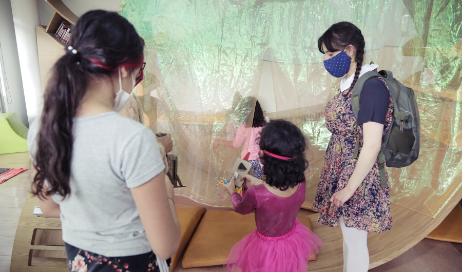 Artistas del Programa Nidos compartiendo con una niña en primera infancia durante experiencia artística.