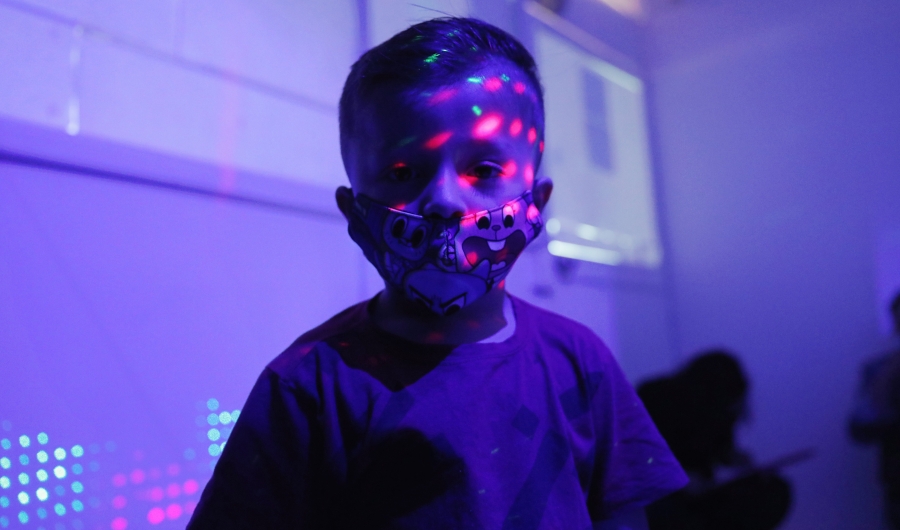 Niño en primera infancia con luces de colores en su rosdtro