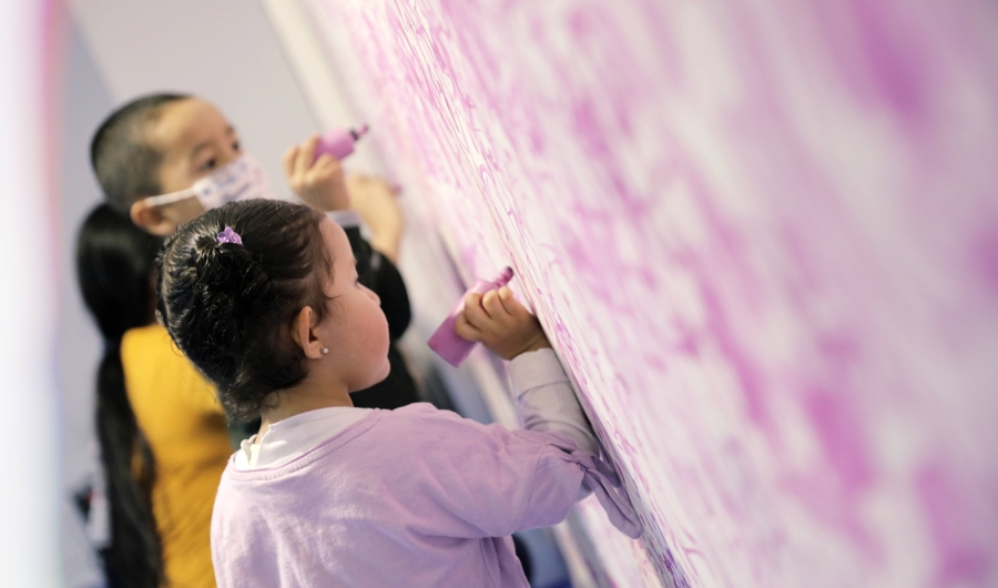 Niños escribiendo con crayola sobre una pared.