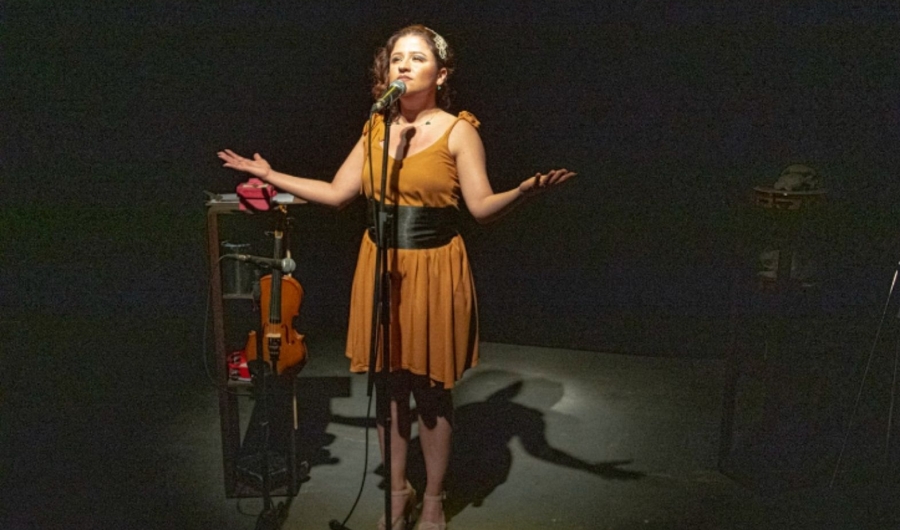 Fotografía de una mujer en escena cantando frente a un micrófono