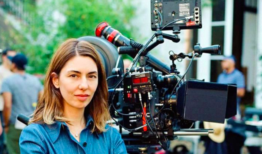 Mujer posando con cámara de cine de fondo 