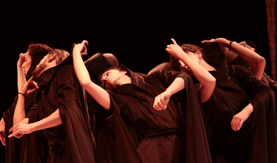 Artistas danzando vestidos de negro en escenario