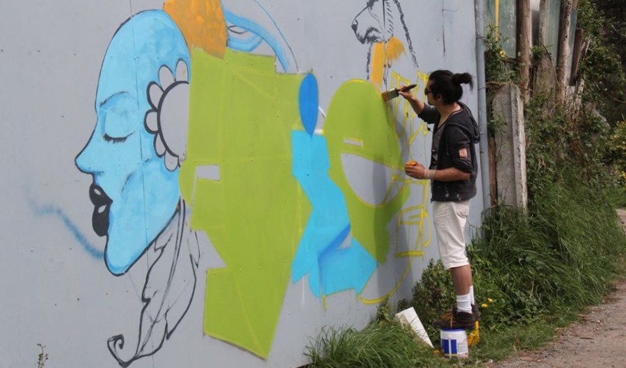 Hombre pinta con brocha un mural en el exterior de día