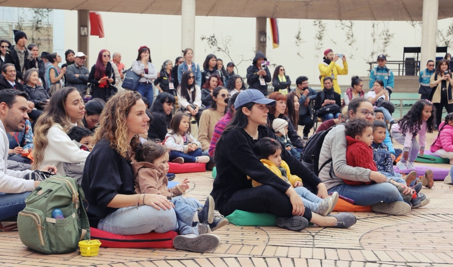 Personas con bebés sentados en el piso viendo presentación