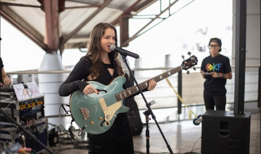 Emilia vestida de negro, con su guitarra y cantando en tarima 