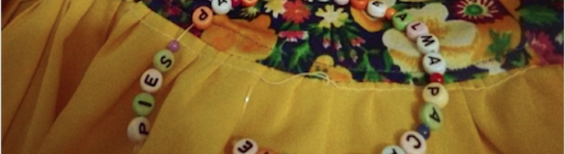 Falda de flores con las letras de la obra en un collar de cuadritos