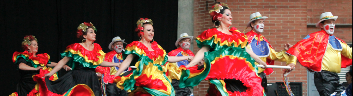 Personas bailando en un escenario con trajes coloridos.