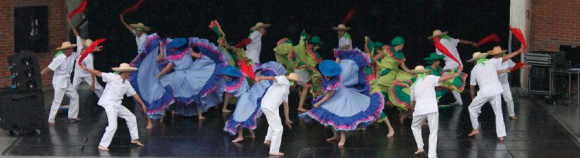 Personas danzando en el escenario con trajes coloridos.