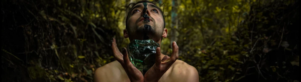 hombre sosteniendo una roca verde con sus manos con una selva de fondo. 