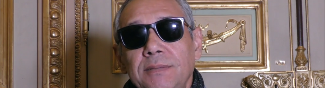 Escritor con gafas oscuras dando una entrevista - Captura de pantalla de entrevista con Casa América.