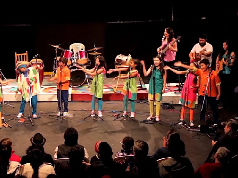 Niños y jovenes en el escenario con instrumentos musicales