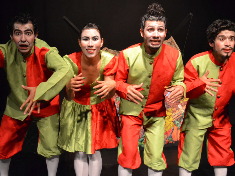 Cuatro actores posando en el escenario, vestidos de verde y naranja
