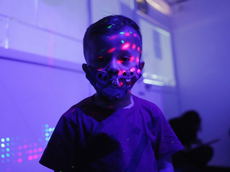 Niño en primera infancia con luces de colores en su rosdtro