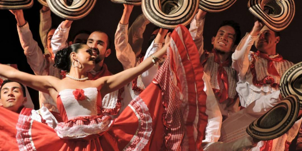 Bailarines vestidos de rojo y blanco con sombreros danzando.