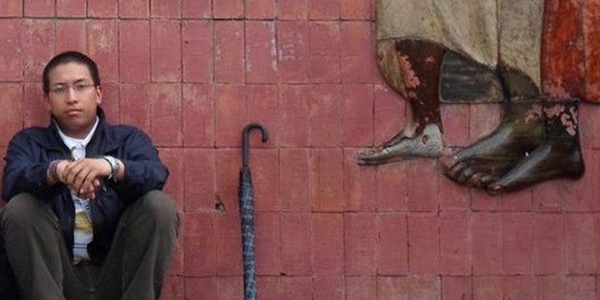 Omar Garzón sentado contra una pared de ladrillos - fotografía de la cuenta de twitter del escritor