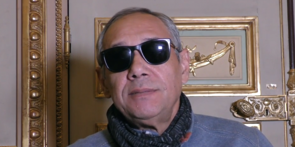 Escritor con gafas oscuras dando una entrevista - Captura de pantalla de entrevista con Casa América.