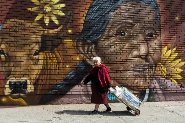Adulto mayor caminando frente  a un grafiti