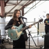 Emilia vestida de negro, con su guitarra y cantando en tarima 